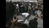 A man walking and jumping on broken pieces of glass on Venice Beach.