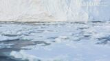 Timelapse of broken pieces of sea ice floating out of bay in front of ice shelf, Antarctica.